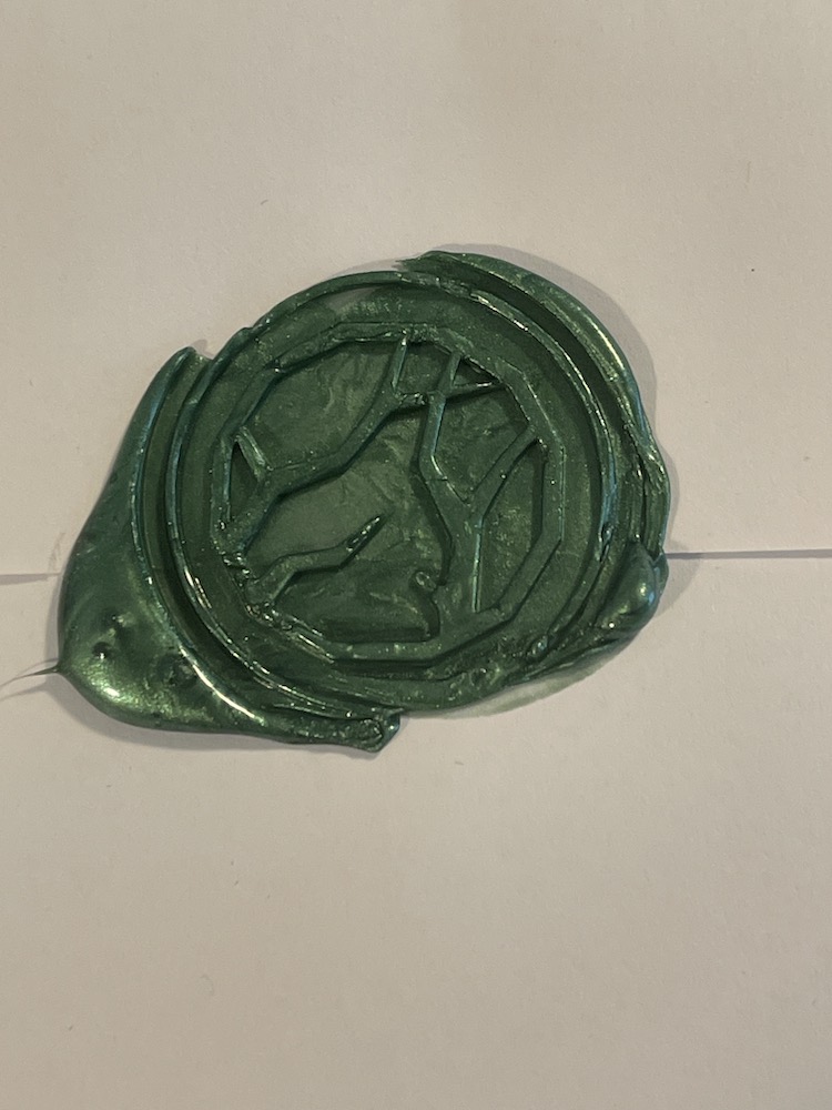 A wax seal, pressed firmly onto an envelope.  It includes the aforementioned design, with a circle around the symbol, and while the symbol is a bit rough around the edges, it is complete.